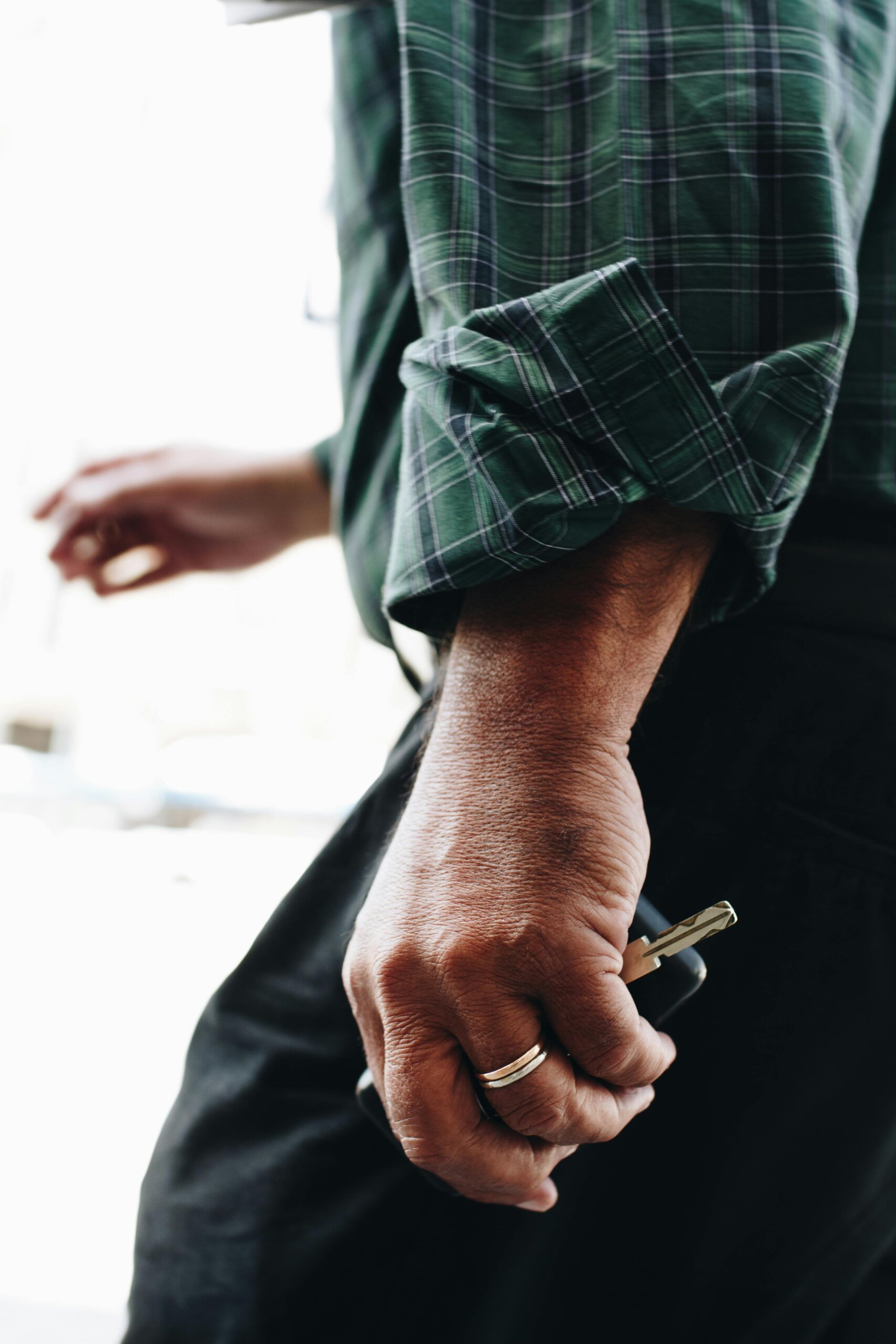 Close-up image of a man's hand holding a key, wearing a ring, in São Miguel, Portugal.